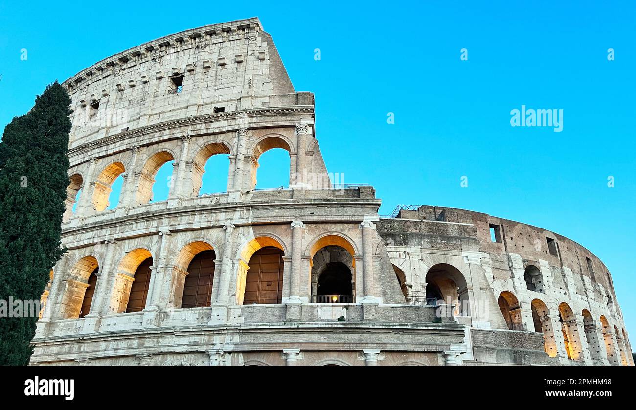 La maestosità del Colosseo visto dal basso in una bella giornata estiva. I raggi del sole illuminano l'antica struttura. Foto Stock