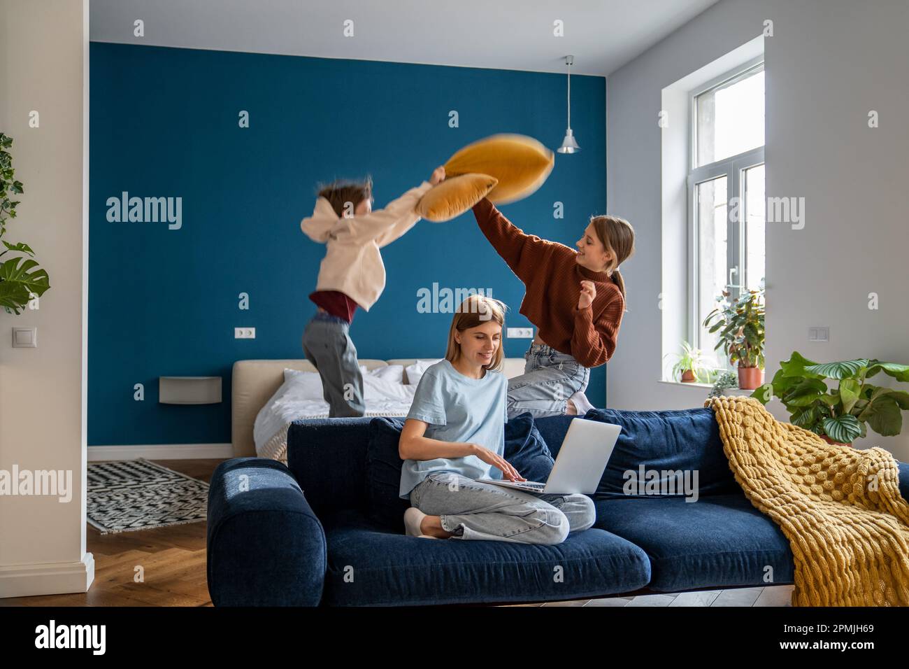 Donna sorridente madre freelancer che lavora da casa mentre guarda i bambini Foto Stock