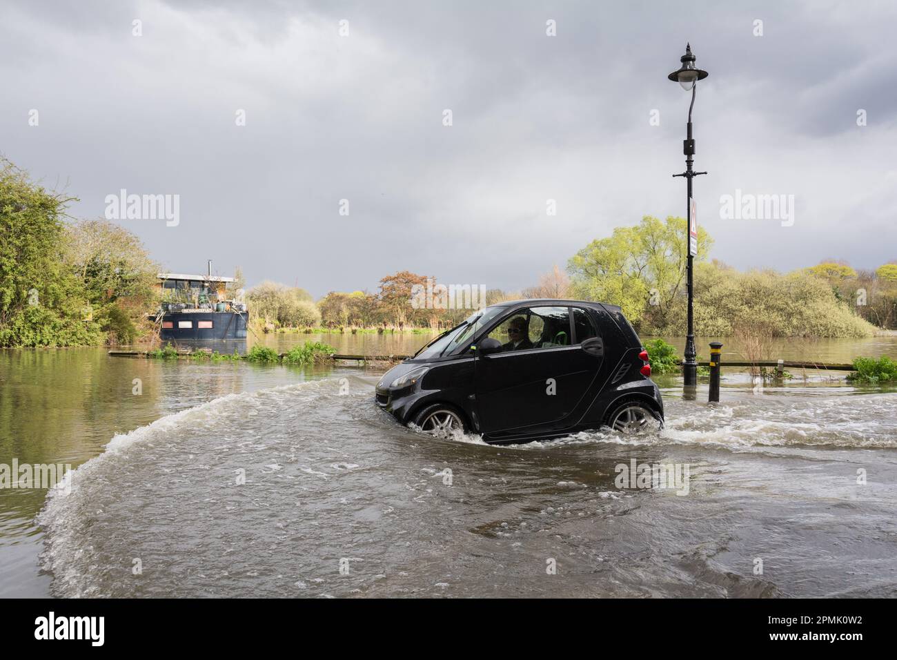 Un'auto intelligente e un motorista che si battono attraverso un fiume Tamigi in piena sul Mall di Chiswick, Londra sud-occidentale, Inghilterra, Regno Unito Foto Stock