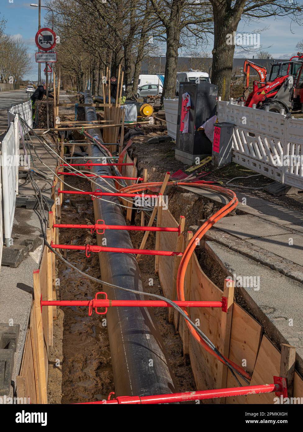 Interramento di tubi di teleriscaldamento in una strada, un cantiere di costruzione a Frederikssund, Danimarca, 13 aprile 2023 Foto Stock