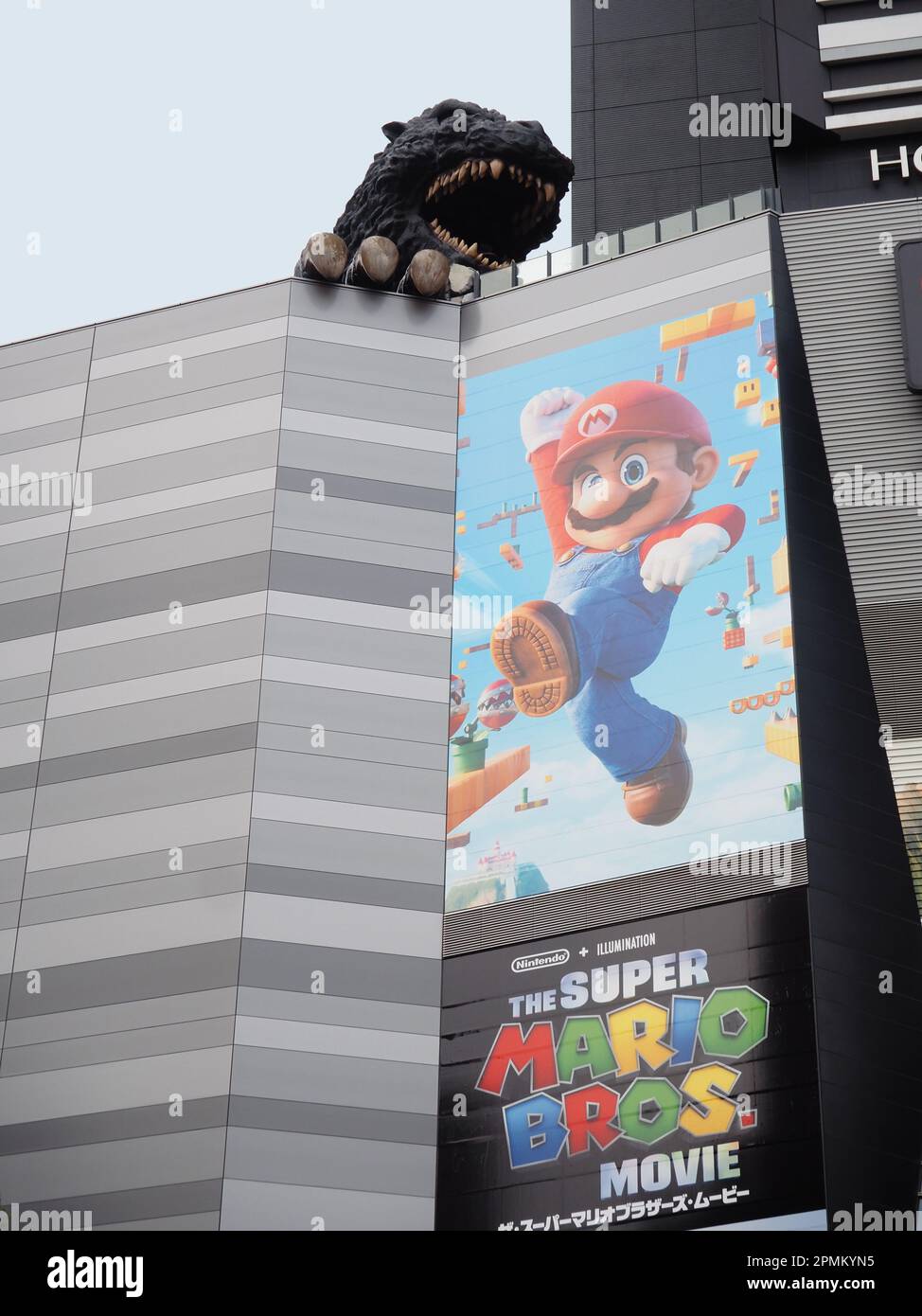 TOKYO, GIAPPONE - 12 aprile 2023: Statua di Godzilla su un cinema Toho a Shinjuku che ha un poster per il Super Mario Bros. Film su di esso. Foto Stock