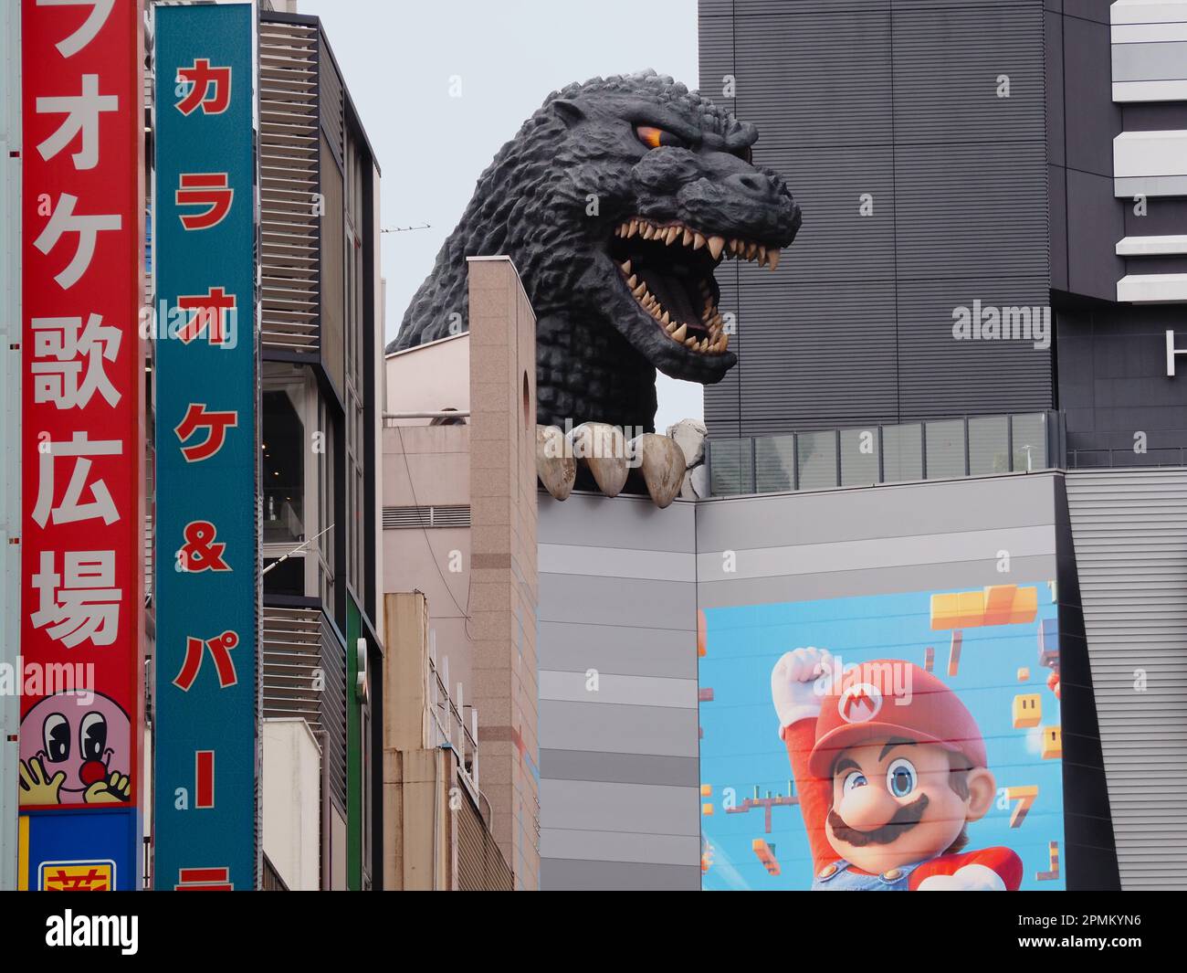 TOKYO, GIAPPONE - 12 aprile 2023: Statua di Godzilla su un cinema Toho a Shinjuku che ha un poster per il Super Mario Bros. Film su di esso. Foto Stock