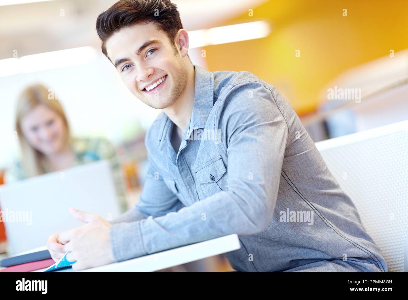 Studiare duro per rendere i suoi genitori orgogliosi. Attraente studente maschio con il suo compagno di studio in background. Foto Stock