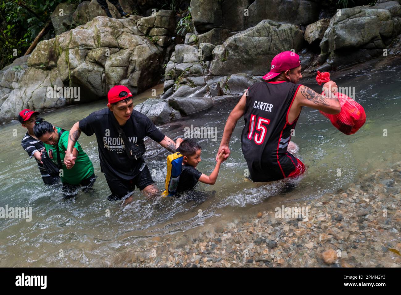 Una famiglia di migranti ecuadoriani, aiutandosi a vicenda, svanisce attraverso il fiume nella giungla pericolosa del Darién Gap tra Colombia e Panamá. Foto Stock