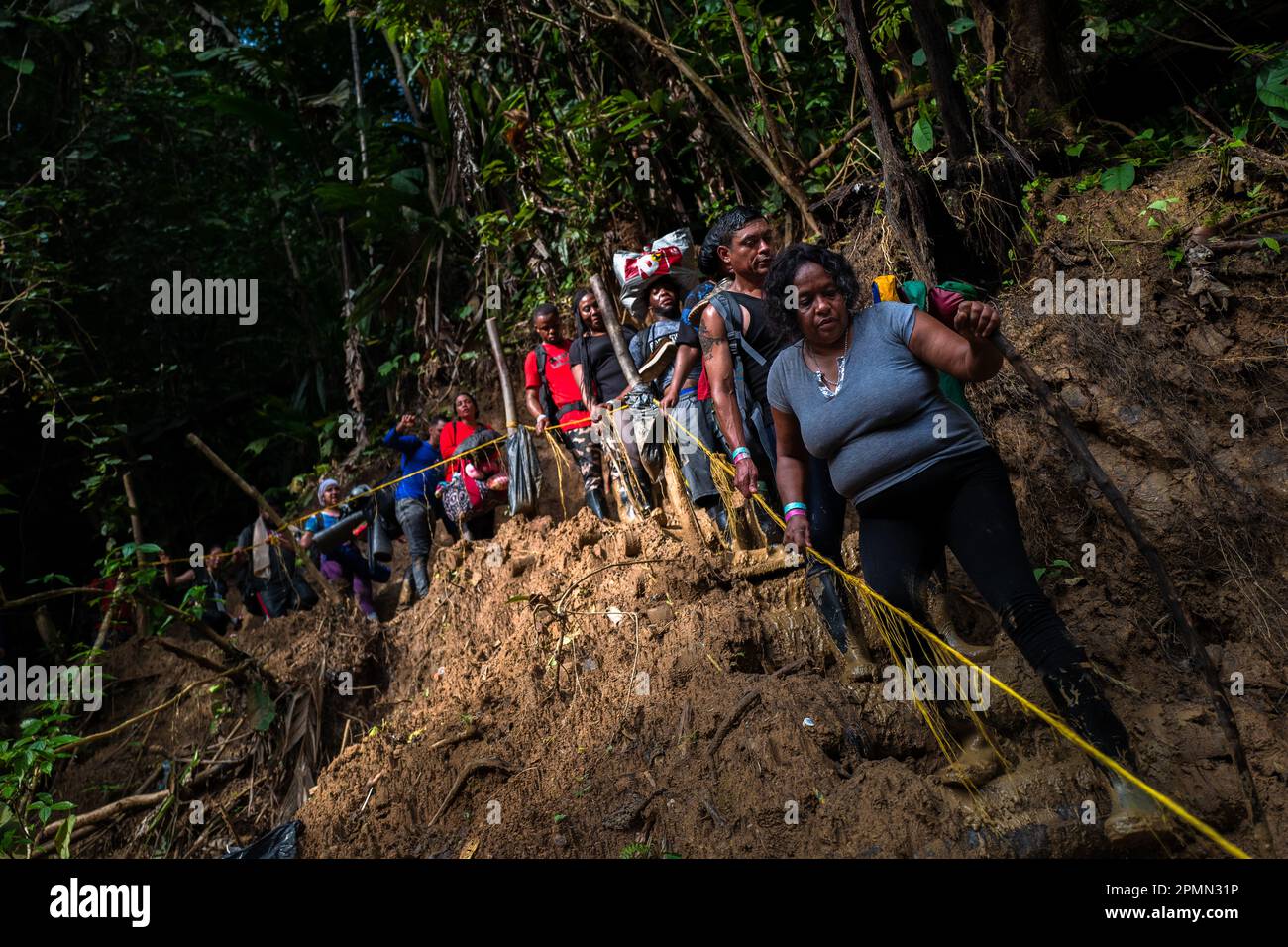 I migranti haitiani salgono lungo un sentiero collinare fangoso nella selvaggia e pericolosa giungla del Darién Gap tra Colombia e Panamá. Foto Stock
