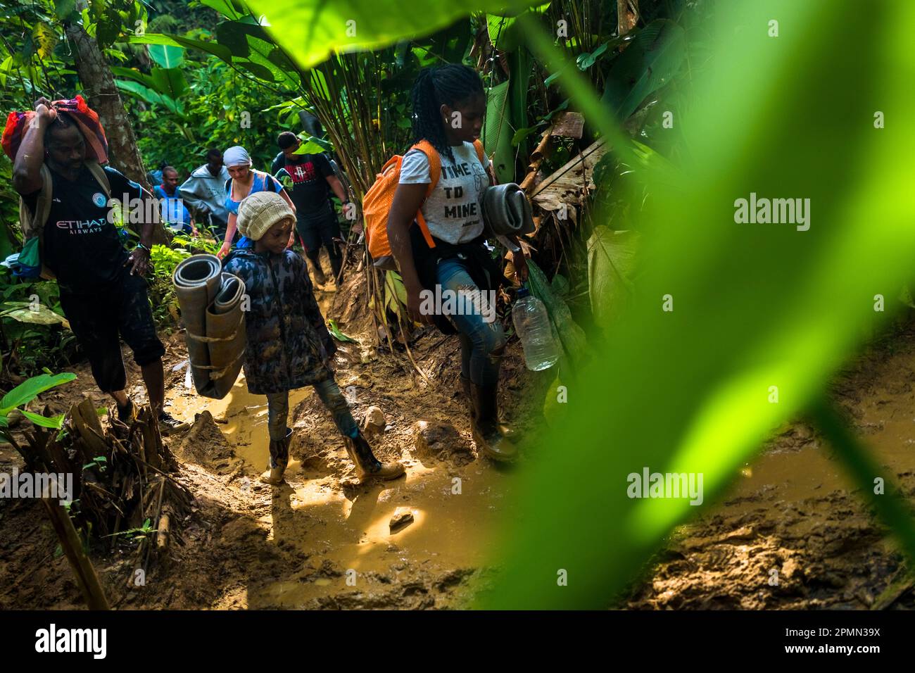 Una famiglia nigeriana migrante cammina attraverso un sentiero fangoso nella giungla selvaggia e pericolosa del Darién Gap tra Colombia e Panamá. Foto Stock