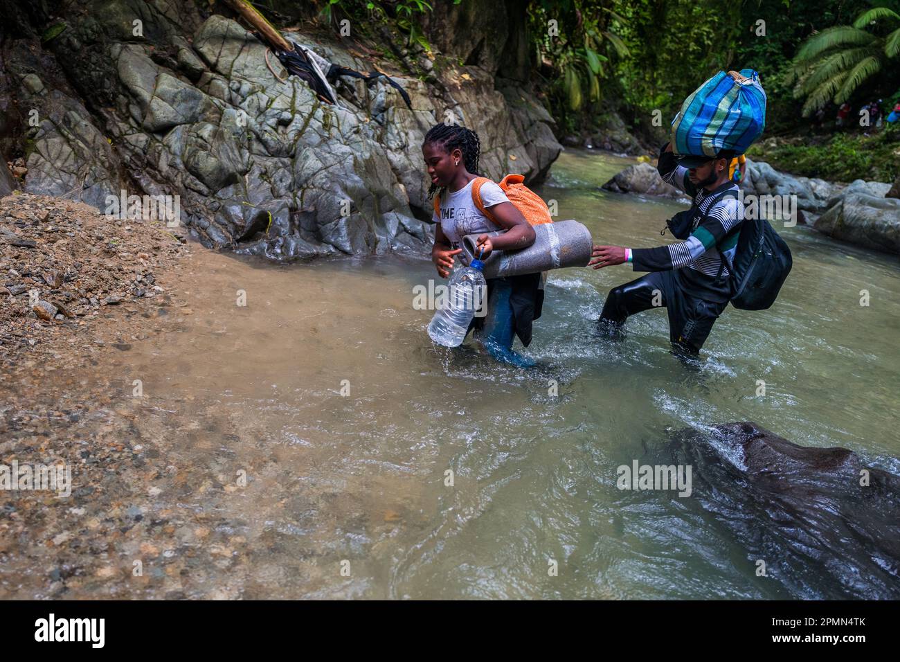 I migranti haitiani gualeggiano attraverso il fiume nella selvaggia e pericolosa giungla del Darién Gap tra Colombia e Panamá. Foto Stock