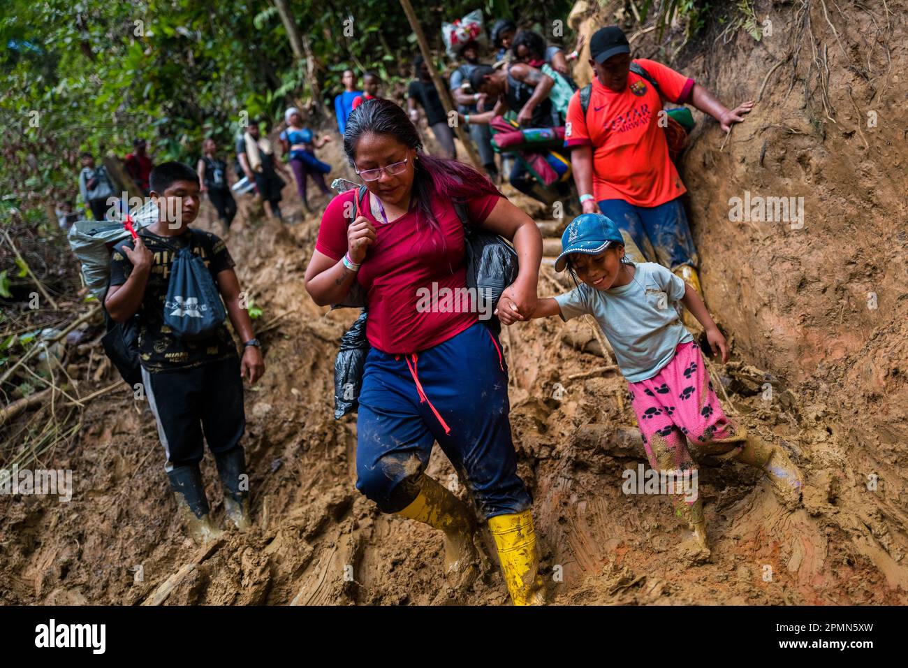 I migranti ecuadoriani si arrampicano su un sentiero collinare fangoso nella selvaggia e pericolosa giungla del Darién Gap tra Colombia e Panamá. Foto Stock