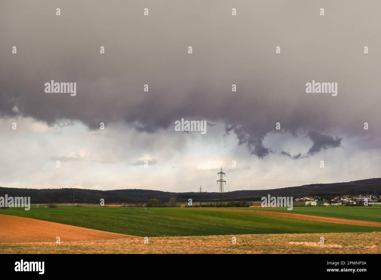 nuvole di pioggia grigie dense durante una tempesta sui campi e sui piloni elettrici nel paesaggio Foto Stock