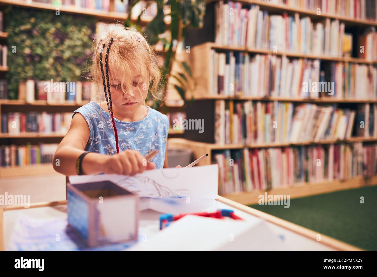 Scolaretta che fa i compiti a casa. Studente elementare imparare, disegnare immagini, fare puzzle alla scrivania in biblioteca scolastica. Studente elementare nel club scolastico Foto Stock