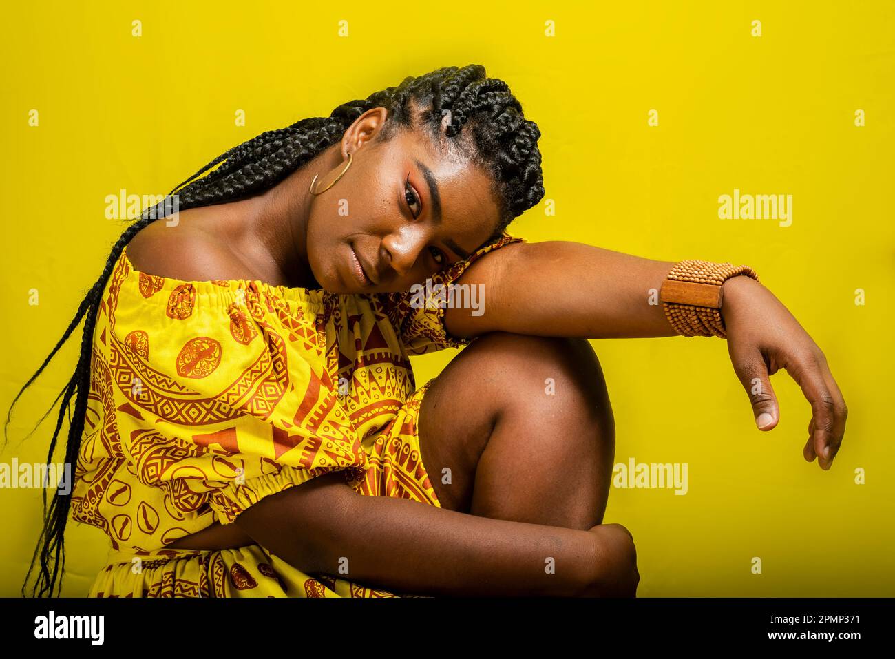 Ritratto di una bella donna, seduta, con la testa abbassata sul braccio. Isolato su sfondo giallo. Foto Stock