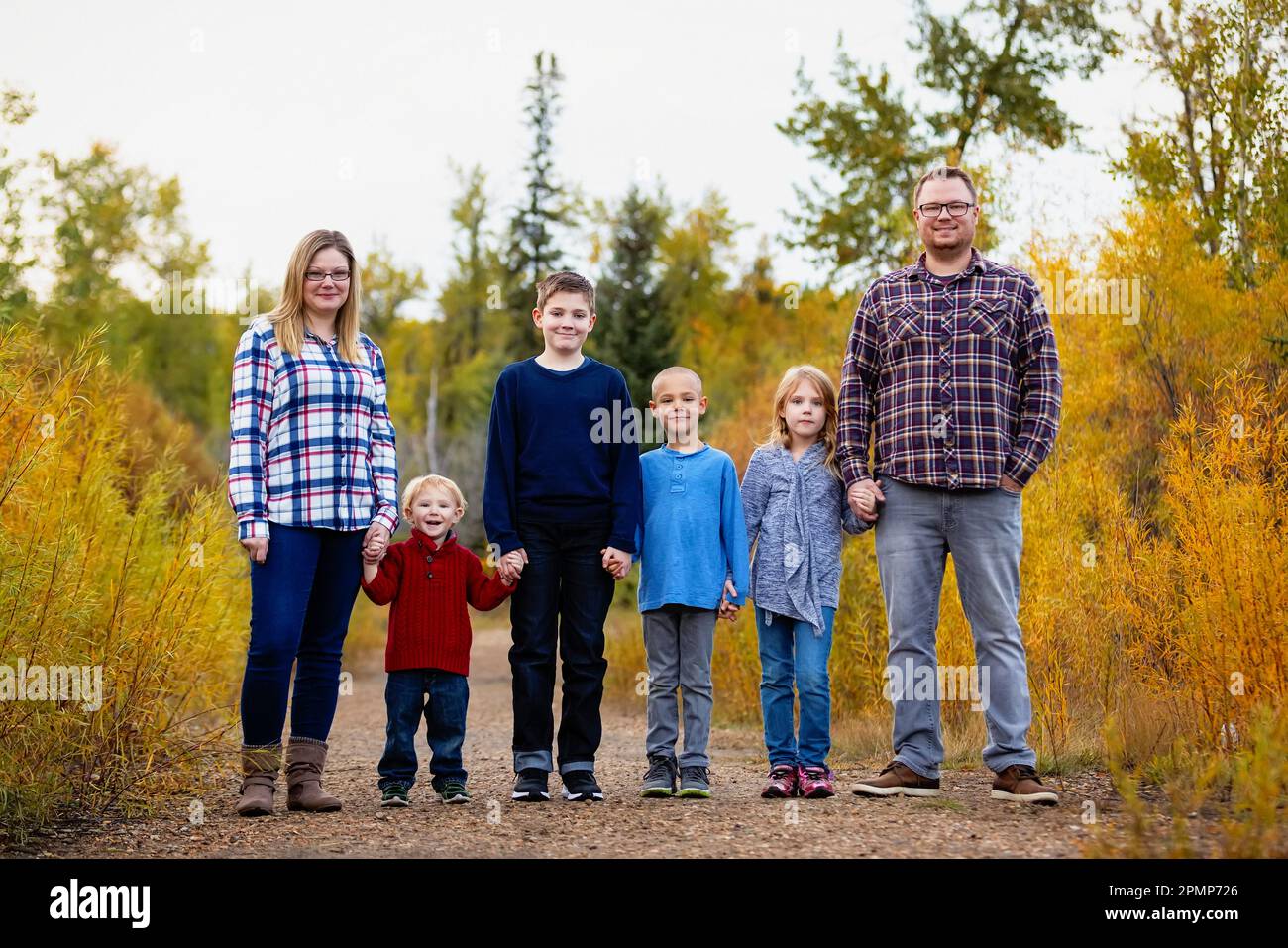 Famiglia di sei persone in piedi insieme mano nella mano in un parco in autunno; Edmonton, Alberta, Canada Foto Stock