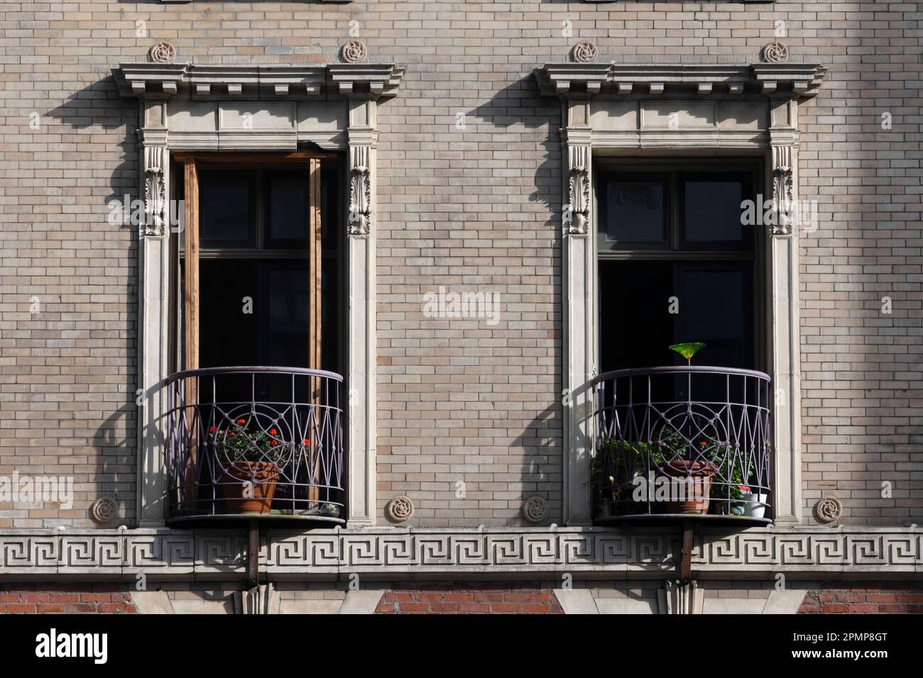 Balconi decorativi su un edificio residenziale. Le ringhiere avvolte in ferro battuto con gerani rossi creano un incantevole ambiente urbano Foto Stock