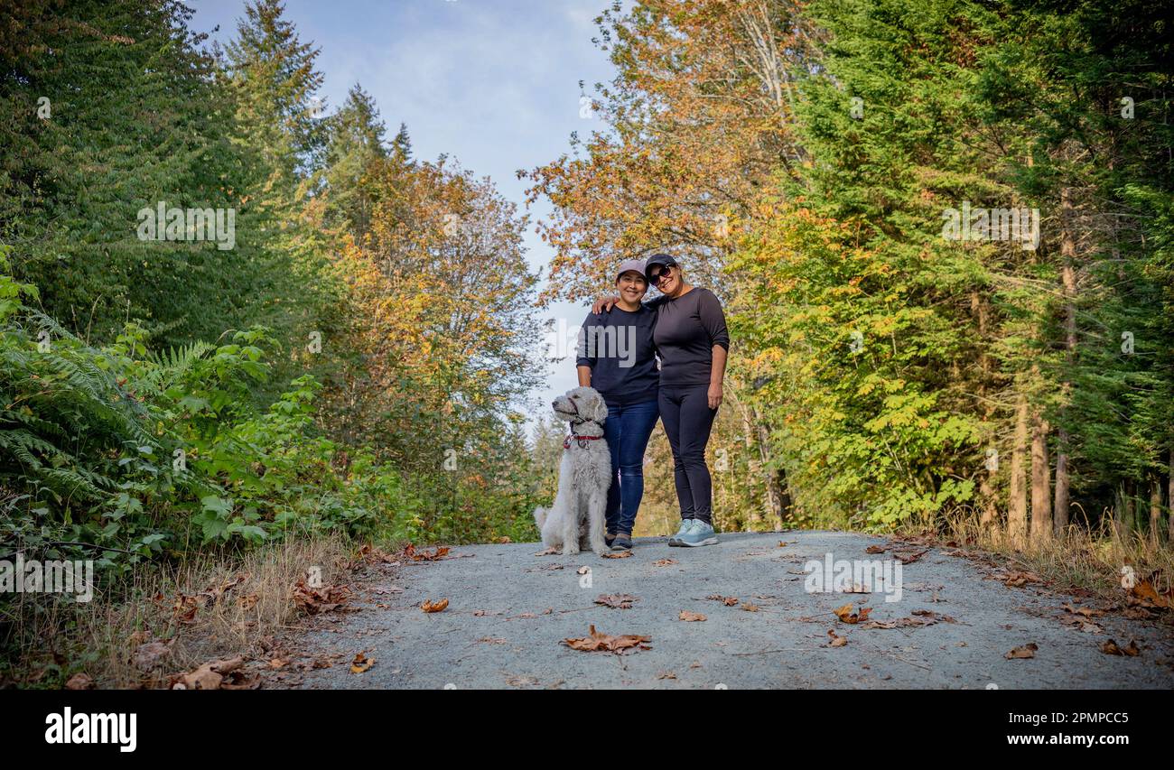 Ritratto di due donne con un cane in un'area del parco; Vancouver Island, British Columbia, Canada Foto Stock