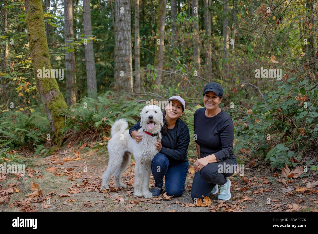 Ritratto di due donne con un cane in una zona boschiva; Vancouver Island, British Columbia, Canada Foto Stock