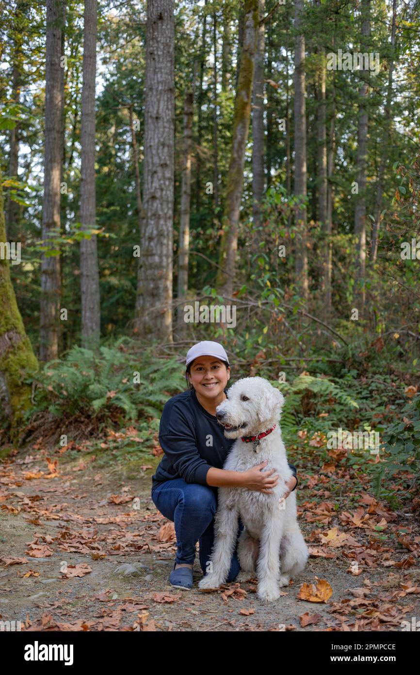 Ritratto di una donna con il suo cane in una zona boschiva; Vancouver Island, British Columbia, Canada Foto Stock
