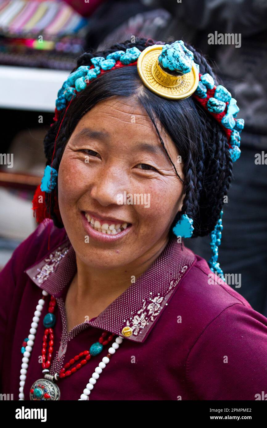 Donna sorridente con accessorio per la testa al mercato Borkhar; Lhasa, Tibet Foto Stock