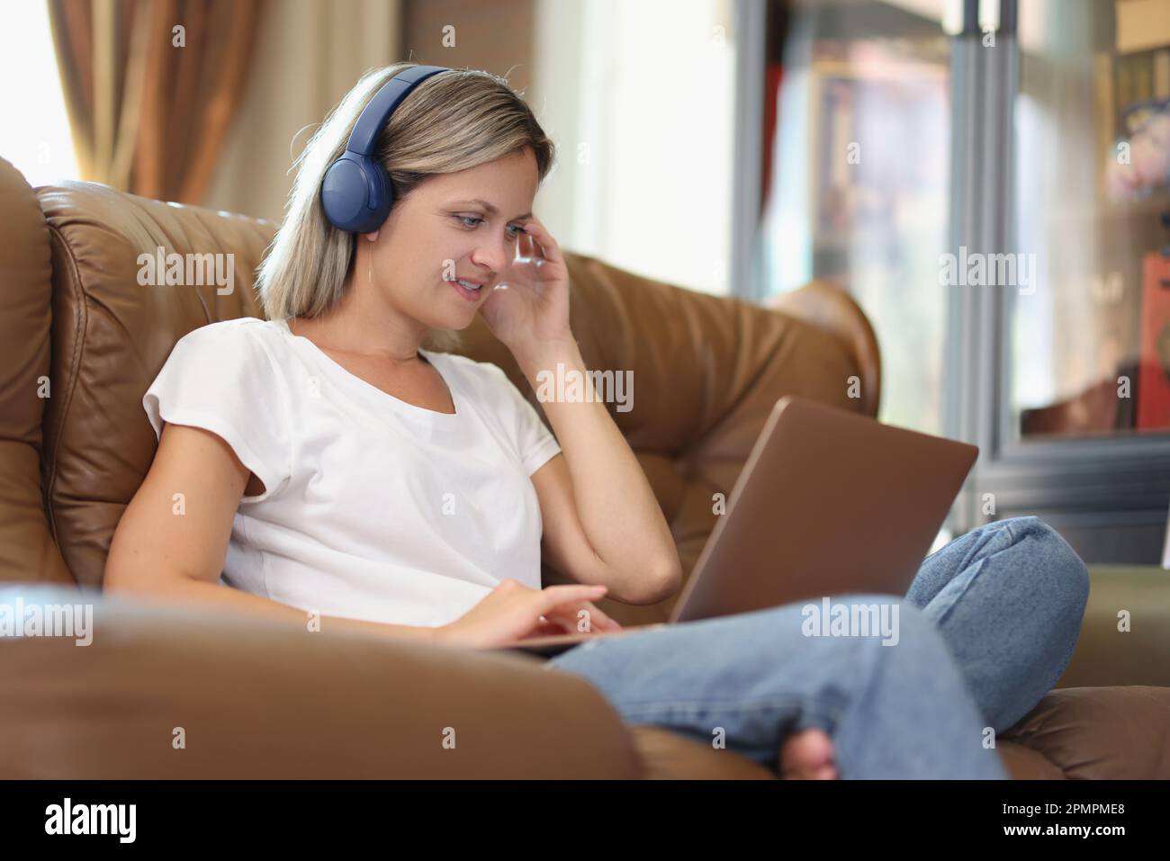Donna lavora su un computer portatile e ascolta la musica con le cuffie Foto Stock