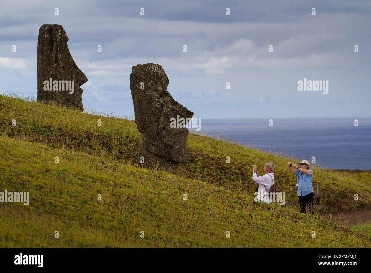 I turisti scattano foto del gigante Moai nel Parco Nazionale di Rapa Nui, sull'Isola di Pasqua; Rano Raraku, Isola di Pasqua Foto Stock