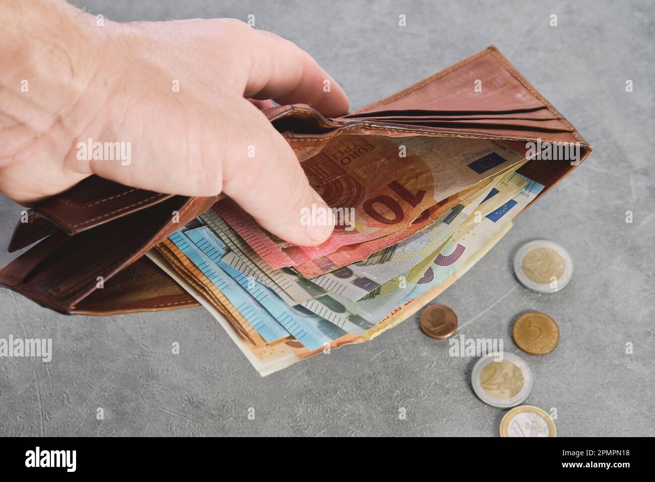 L'uomo anziano tiene un portafoglio con banconote in euro in mano, banconote in euro nel portafoglio. Portafoglio con soldi in mano di un uomo, idea di sfondo di pagamento Foto Stock