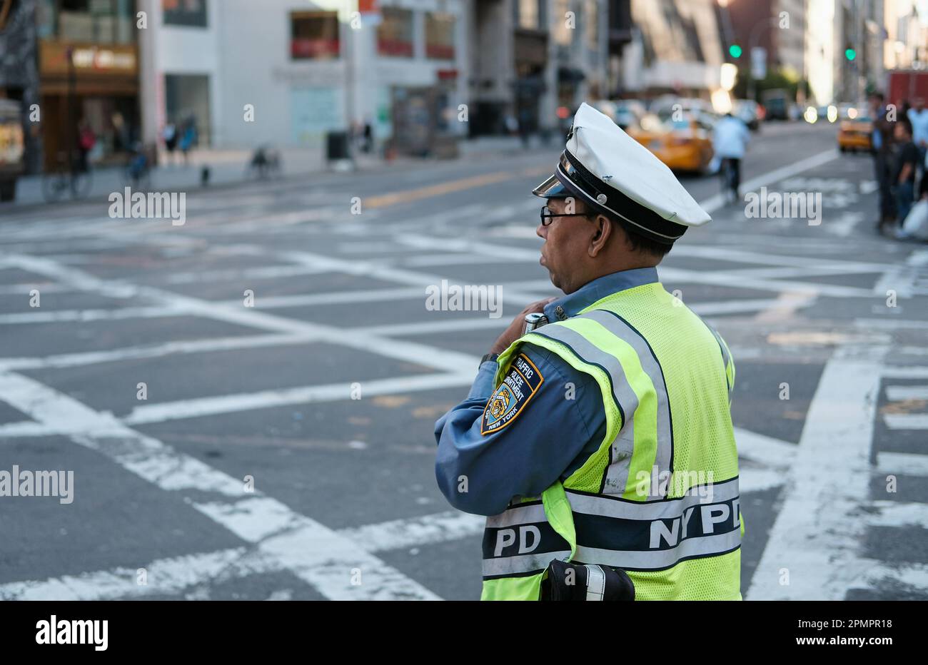 Poco profonda concentrazione di un ufficio del traffico di NYPD visto in servizio in un crocevia affollato della città. Visto indossare il suo equipaggiamento di sicurezza ad alta fedeltà. Foto Stock
