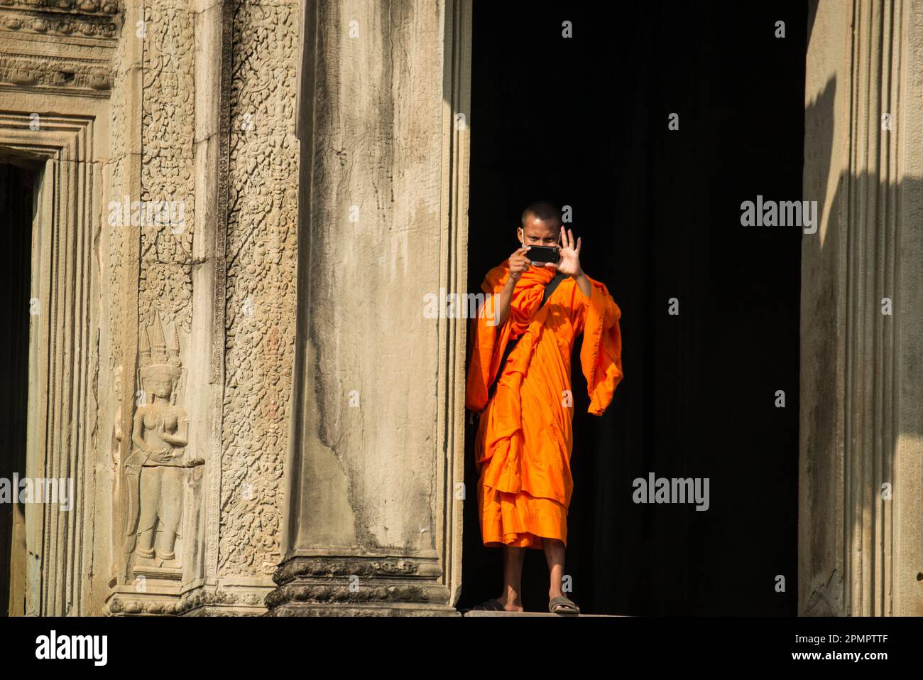 Il giovane monaco buddista usa un cellulare per scattare fotografie ad Angkor Wat; Cambogia Foto Stock