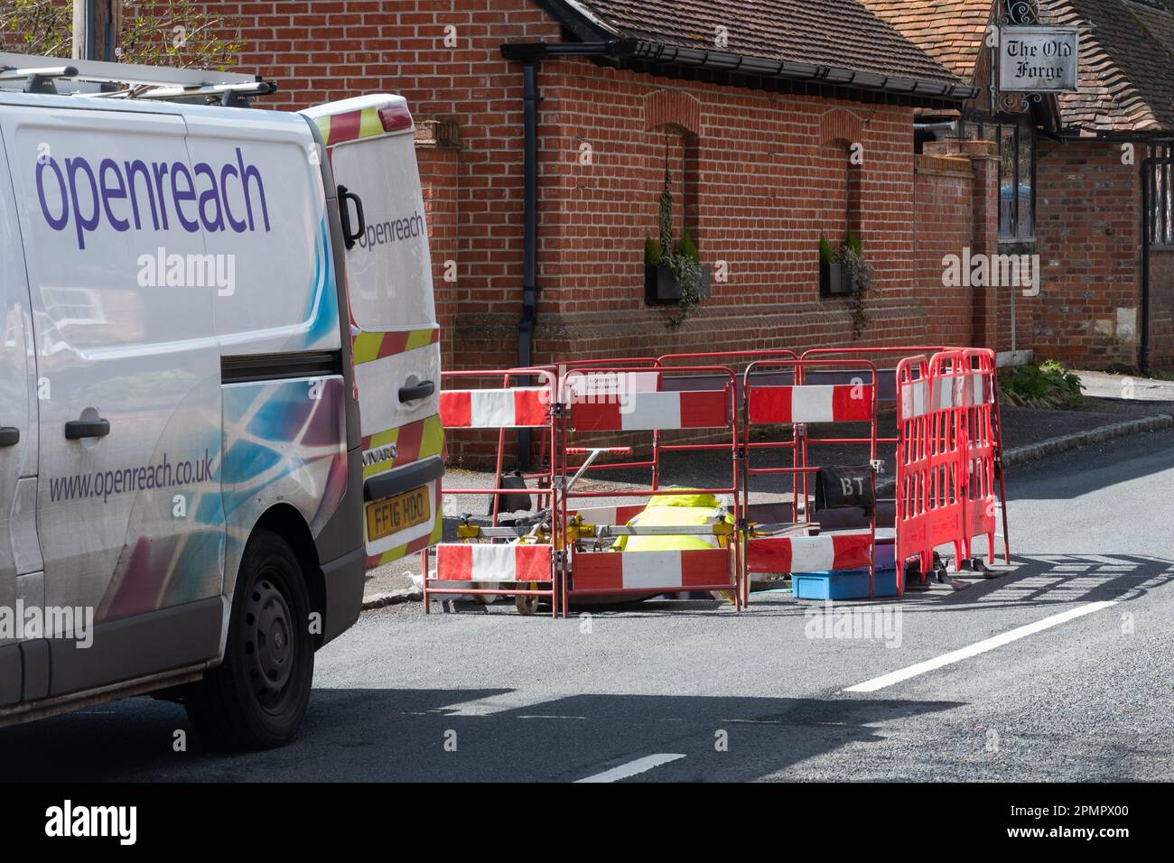 Ingegnere OpenReach che lavora in un buco della strada in un villaggio inglese, Berkshire, Inghilterra, Regno Unito Foto Stock