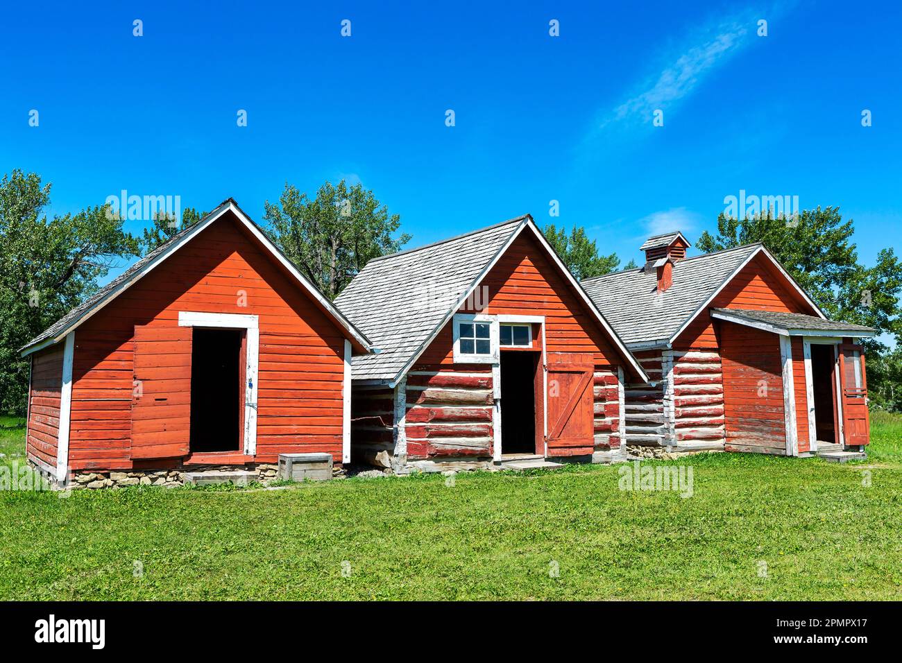 Tre vecchi edifici storici dipinti di rosso con cielo blu, a sud di Longview, Alberta; Alberta, Canada Foto Stock