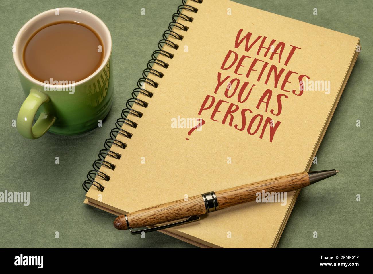 Cosa ti definisce persona? Domanda ispiratrice in un libro di schizzi a spirale con una tazza di caffè, identità e concetto di sviluppo personale. Foto Stock