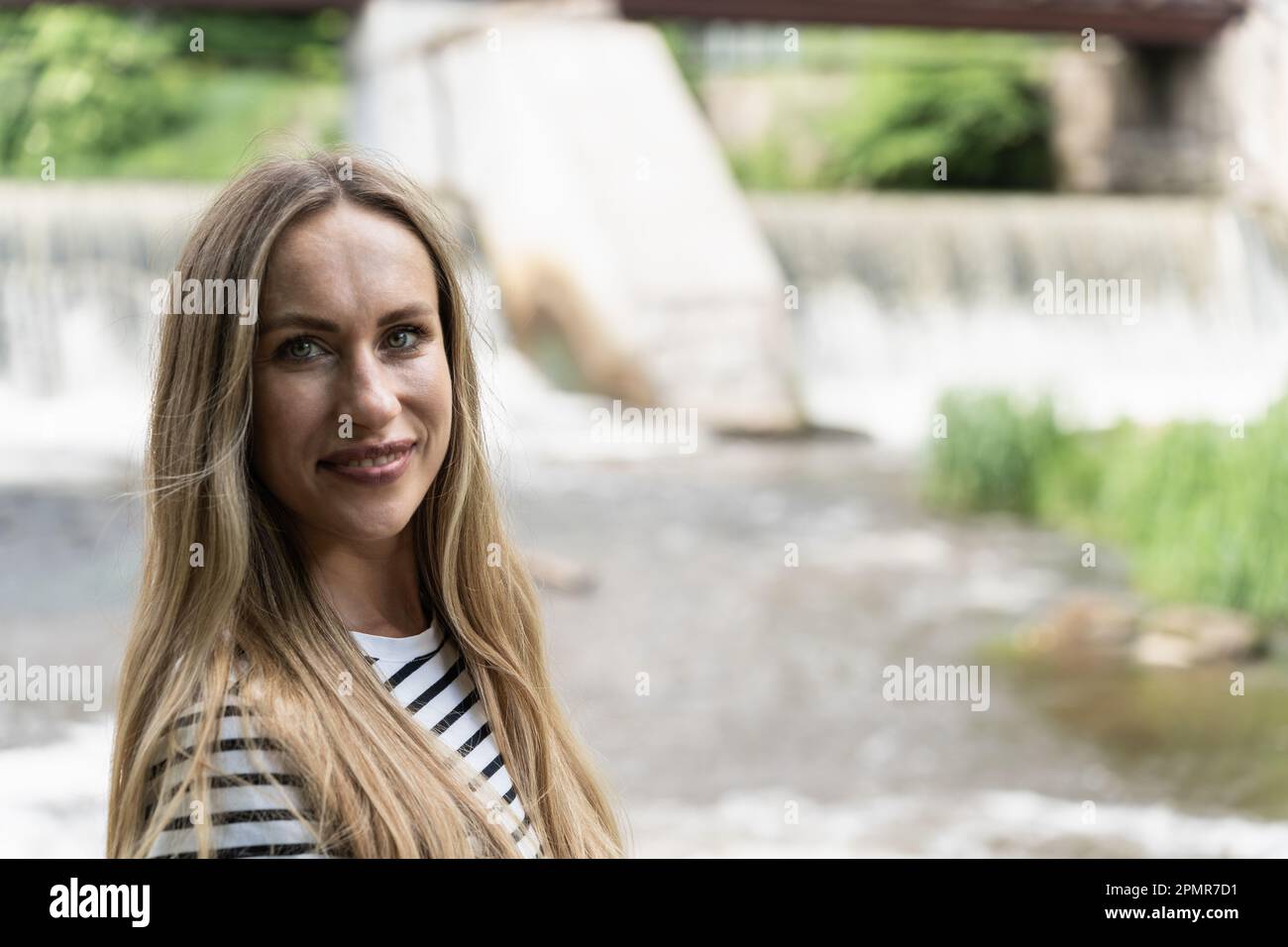 Concentratevi sul primo piano di una donna sorridente dai capelli lunghi sullo sfondo del fiume. Foto Stock