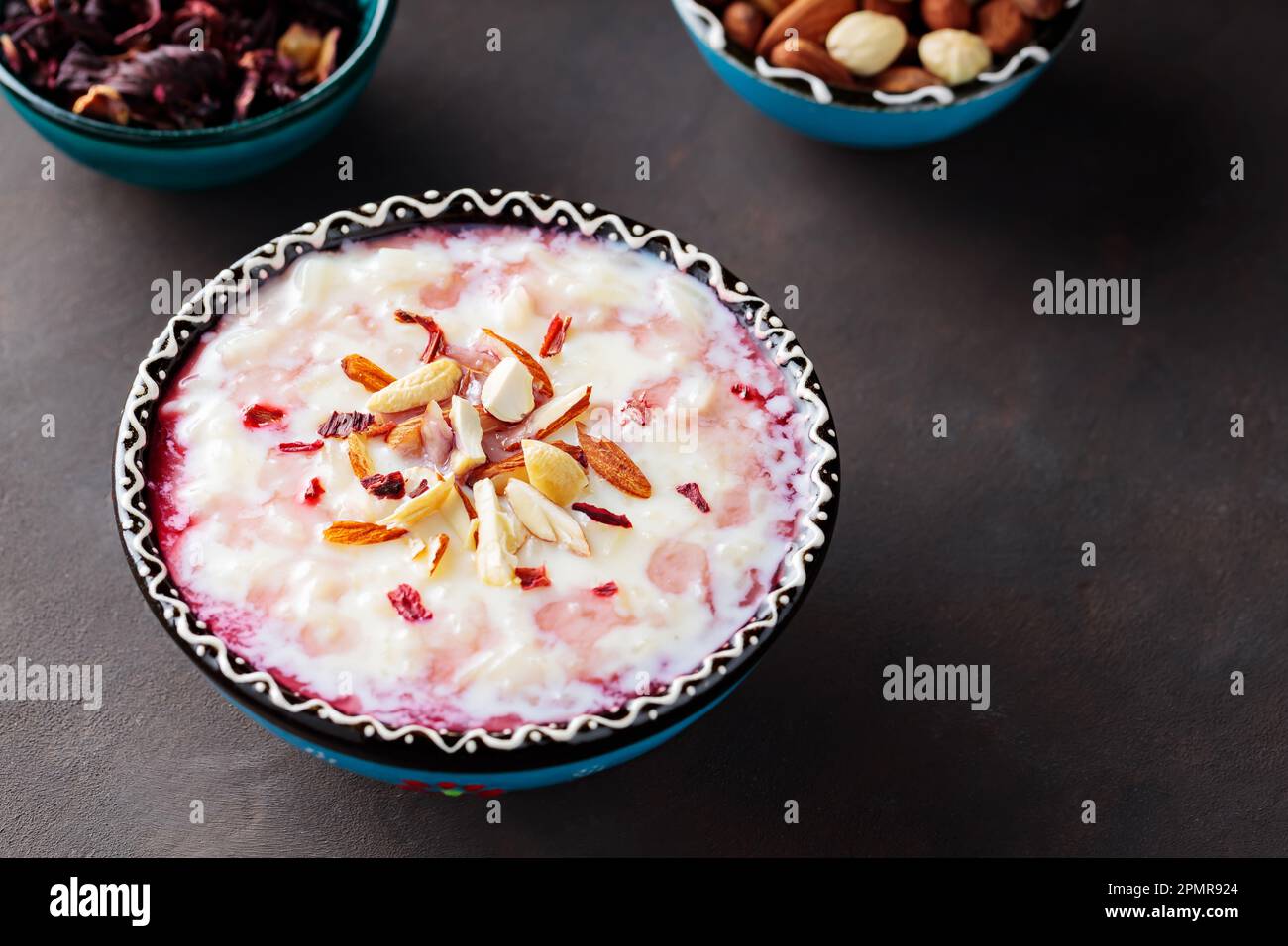Budino di riso con noci cosparse su fondo scuro. Delizioso cicerello di riso con cannella e acqua di rosa hibiscus. Spazio di copia Foto Stock