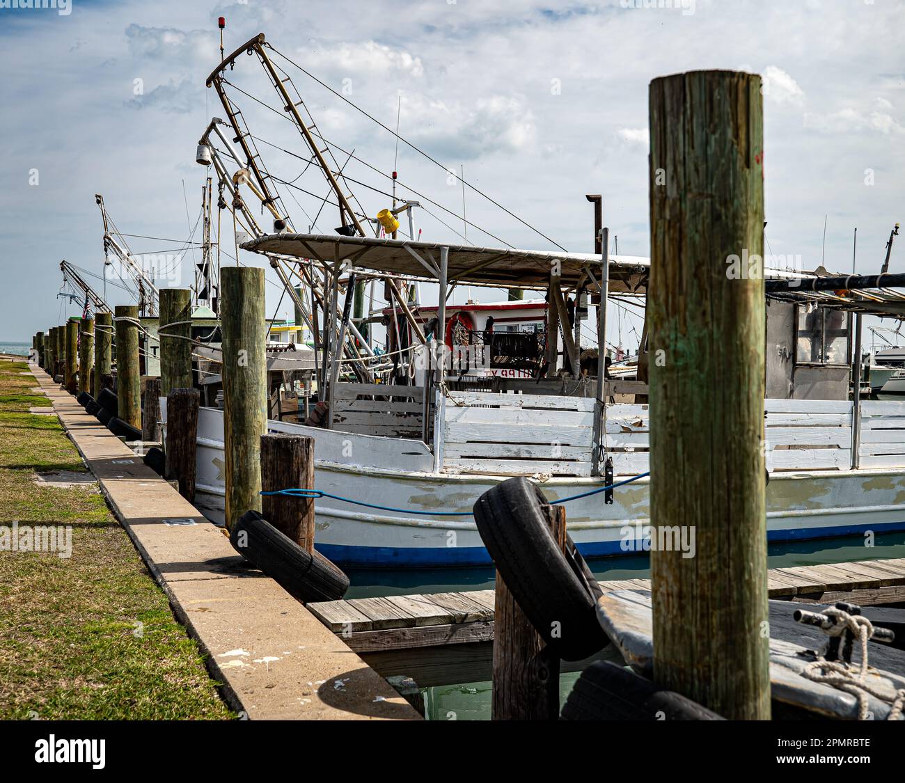 ROCKPORT, TX - 14 FEB 2023: Una fila di pali di legno presso il porto turistico con barche da pesca ormeggiate in una giornata parzialmente soleggiata in Texas. Foto Stock