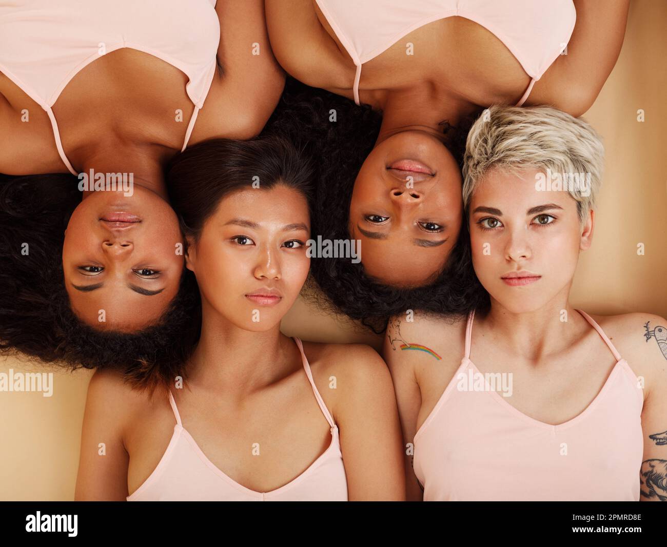 Gruppo di quattro donne che si trovano insieme in uno studio e guardano la telecamera. Femmine diverse che si trovano testa a testa. Foto Stock
