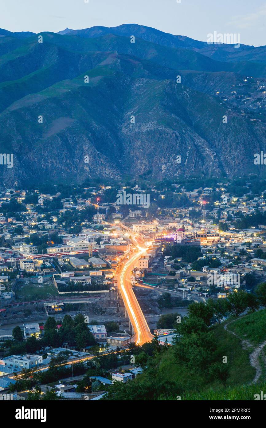 Una vista della città di Fayzabad in un'ora blu con il sentiero leggero di automobili su un ponte; Badakhshan, Afghanistan Foto Stock