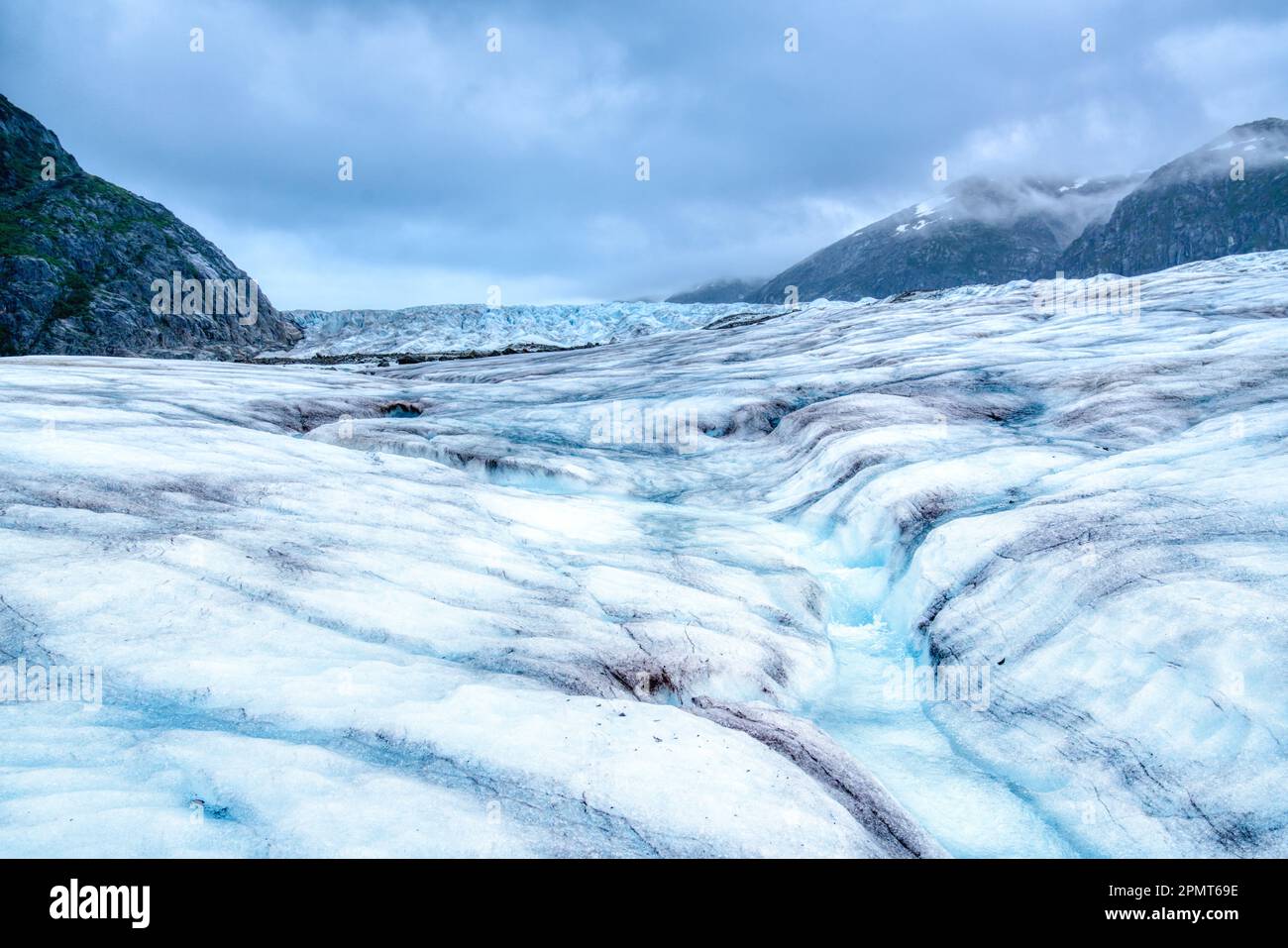 Il ghiaccio fondente del ghiacciaio Mendenhall in Alaska forma un flusso tortuoso di acque cristalline e blu Foto Stock