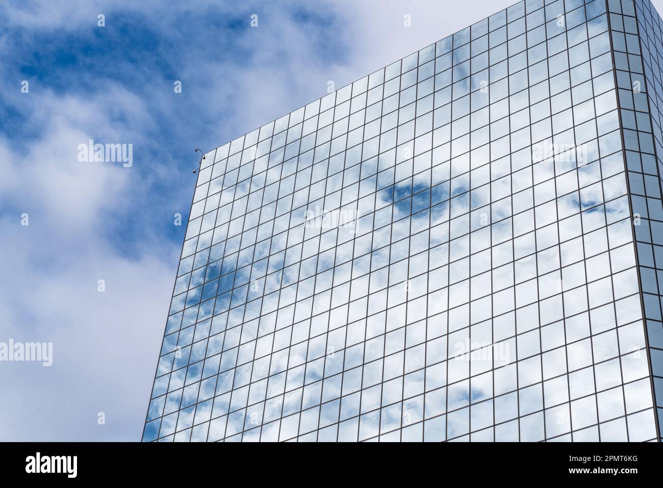 Le nuvole e il cielo blu si riflettono su un alto grattacielo in vetro a specchio Foto Stock