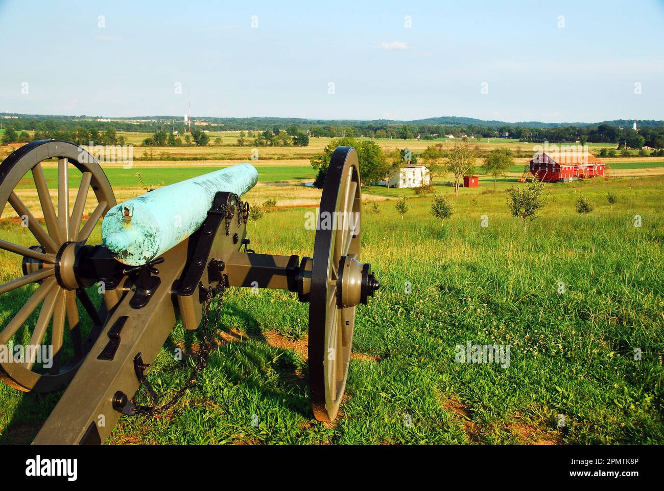 Un cannone dell'epoca della Guerra civile guarda giù sulle strutture agricole del Parco militare Nazionale di Gettysburg in Pennsylvania Foto Stock