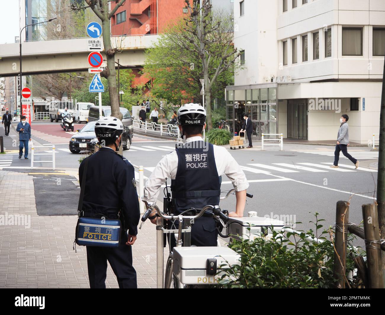 TOKYO, GIAPPONE - 6 aprile 2023: Agenti di polizia con biciclette e caschi da bicicletta che guardano una strada nell'area di Kyobashi a Tokyo. Foto Stock