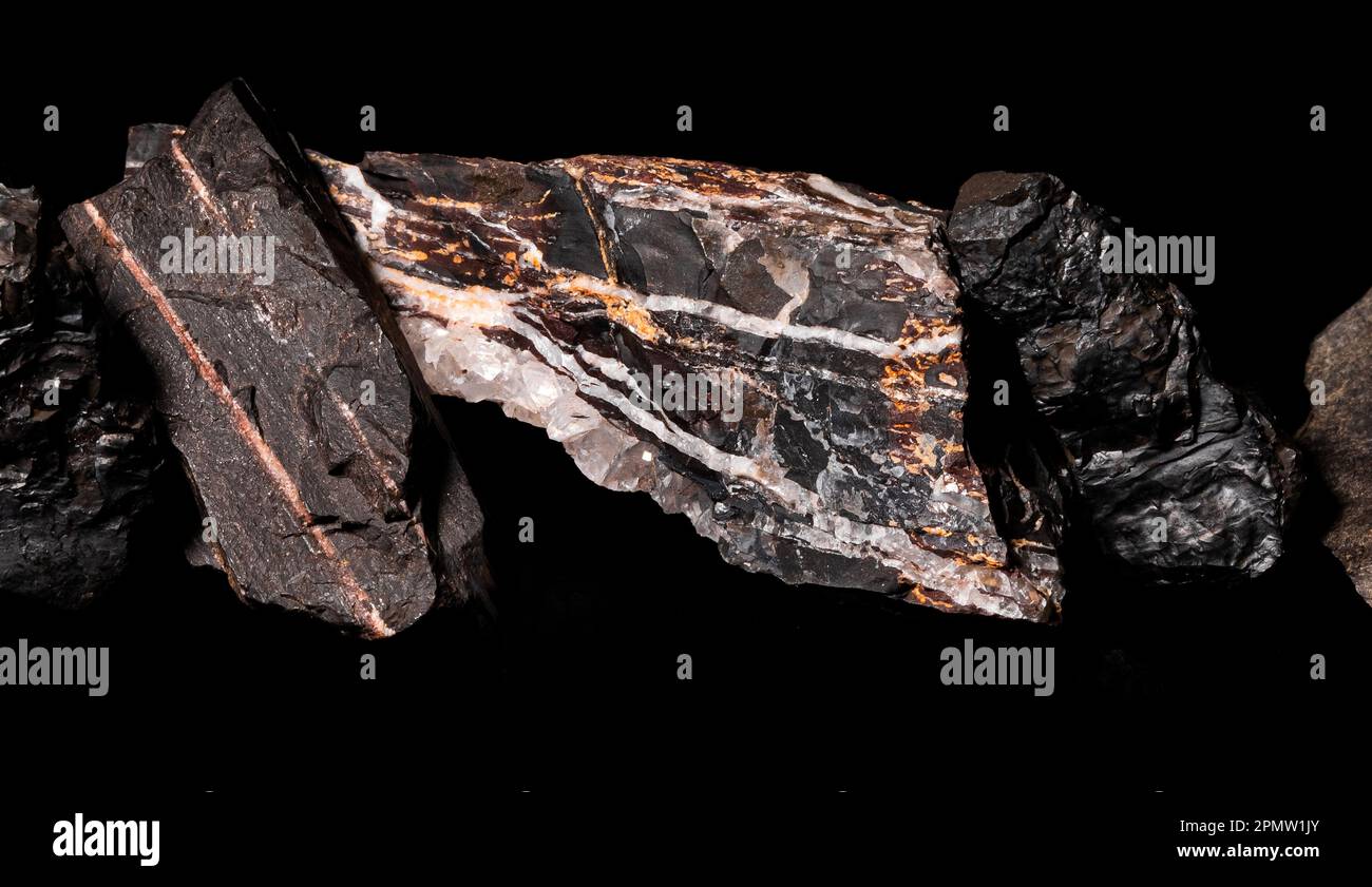 Una roccia minerale con alcune formazioni cristallizzate su sfondo nero, illuminata da un lato per evidenziarne le caratteristiche Foto Stock