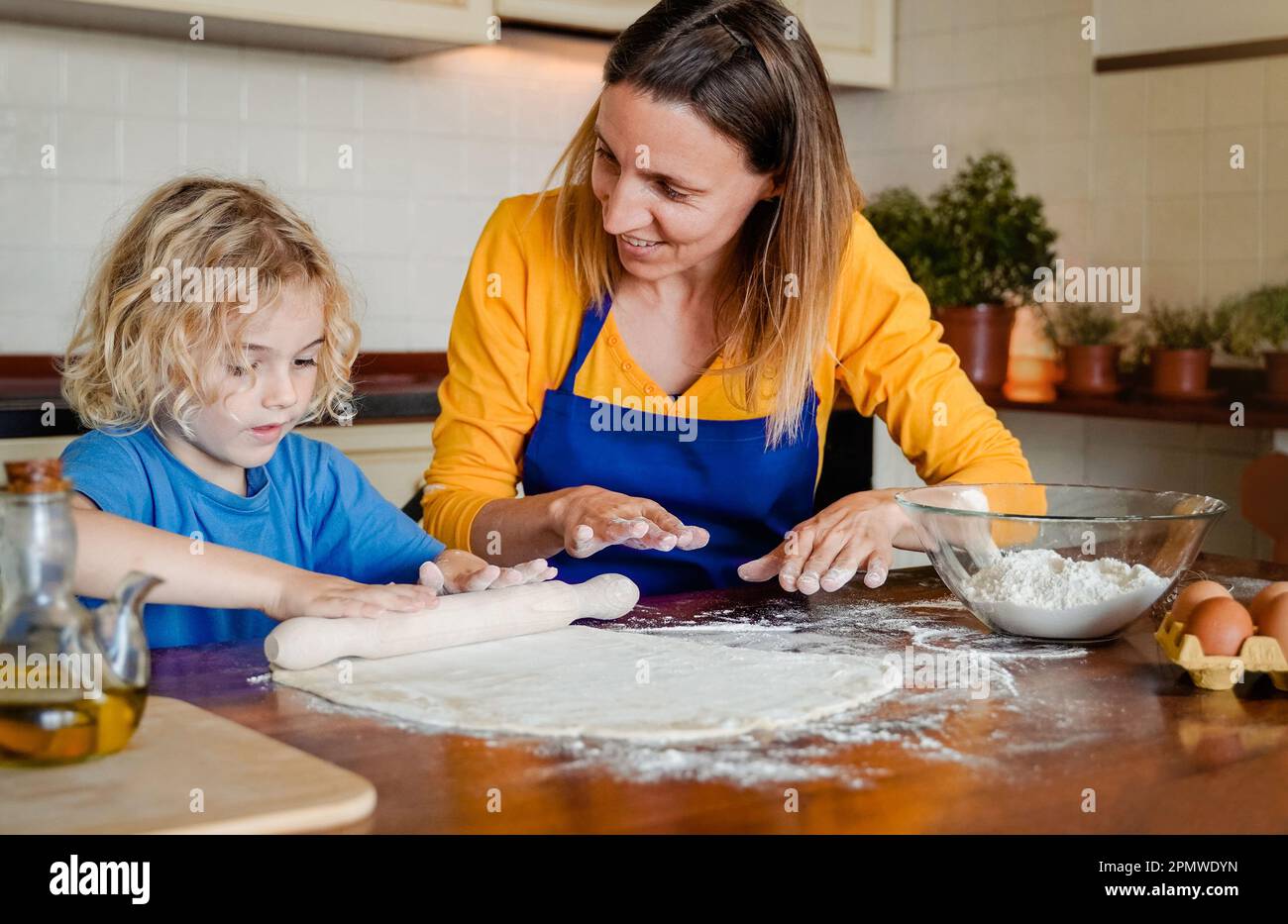 Cucina di famiglia: Madre e figlio felice che si divertono a preparare la pizza pasta all'interno della cucina domestica - fuoco morbido sul viso della mamma Foto Stock