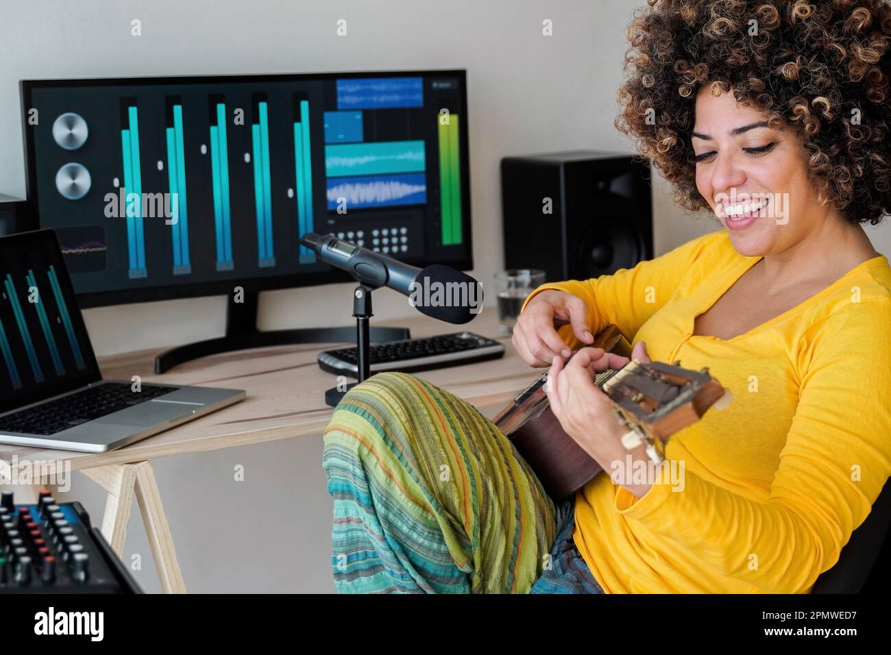 Music home studio - musicista africano donna registrazione ukulele strumento chitarra - artista ingegnere tecnologia Foto Stock