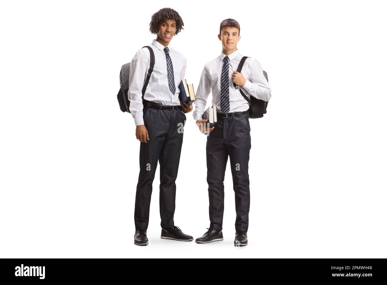Studente maschio afro-americano e caucasico in uniformi che trasportano zaini e posano isolati su sfondo bianco Foto Stock