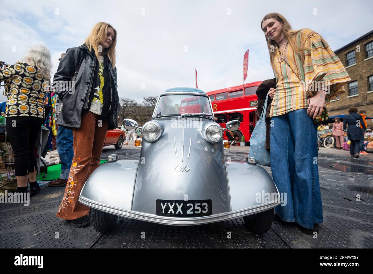 Londra, Regno Unito. 15 aprile 2023. I visitatori in abbigliamento vintage vedono una Messerschmitt KR200, o Kabinenroller, una bolla-car a tre ruote progettata dall'ingegnere aereo Fritz Fend, prodotta nella fabbrica del costruttore tedesco di aeromobili Messerschmitt dal 1955 al 1964, alla Classic Car Boot sale in Granary Square, King’s Cross. L'evento celebra tutte le cose vintage, dalla moda e gioielli ai dischi in gres e vinile, sullo sfondo di veicoli vintage. Credit: Stephen Chung / Alamy Live News Foto Stock