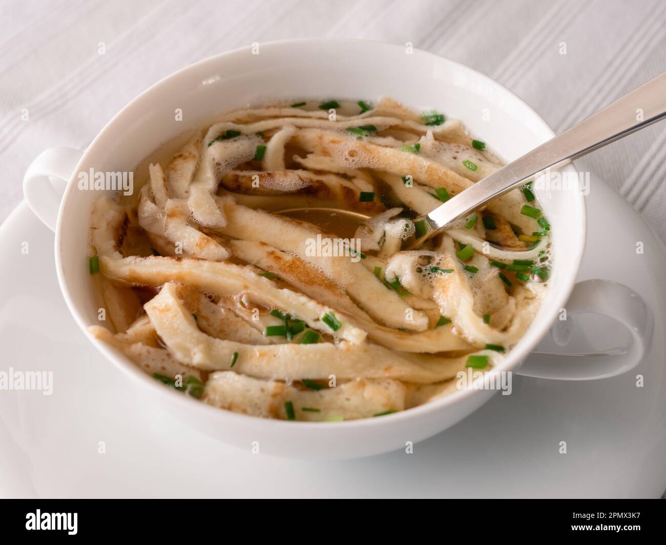 Zuppa austriaca di pancake a fette o Frittatensuppe con erba cipollina, un brodo di manzo trasparente Foto Stock