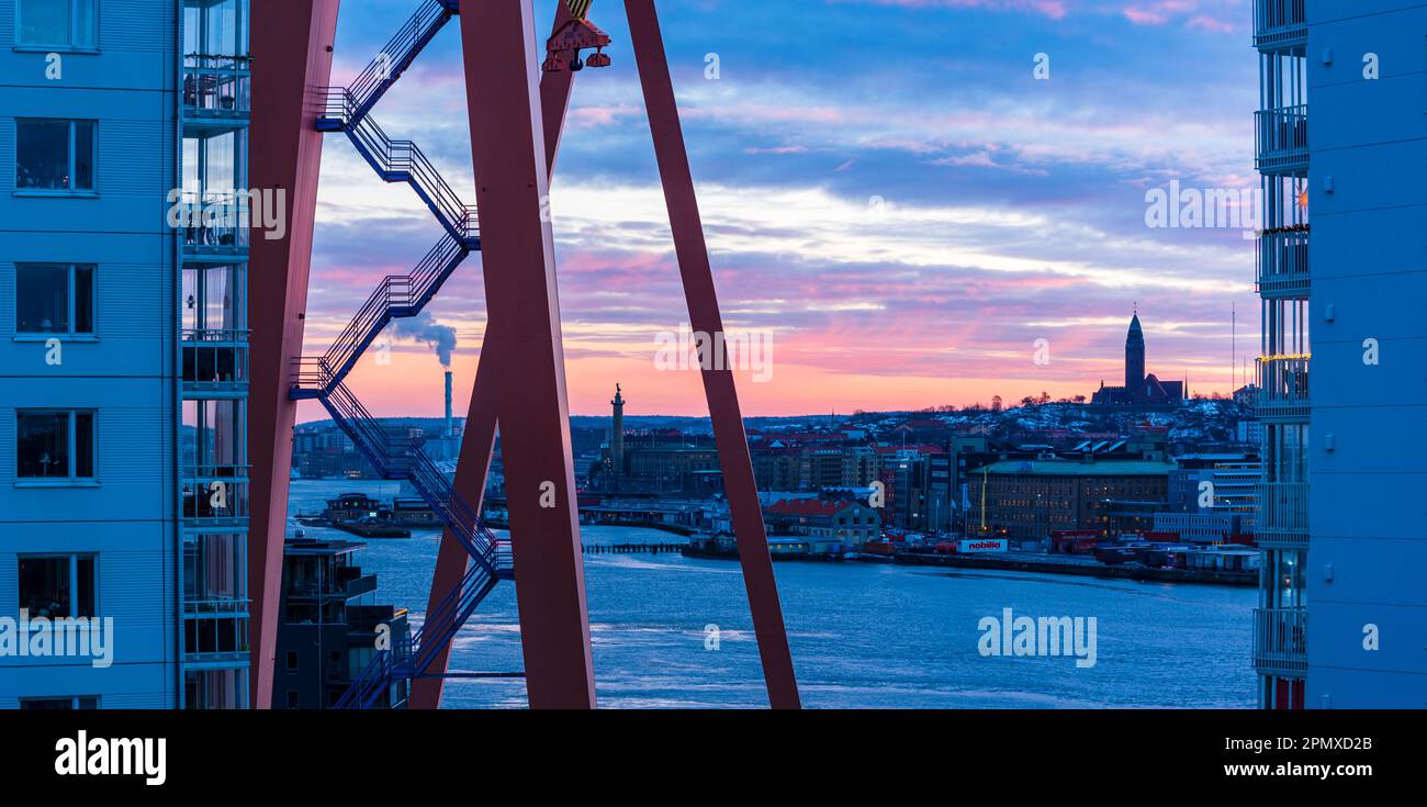 All'alba, un cielo rosa illumina la struttura costruita della zona residenziale di Gothenburgs lungo il fiume con la sua architettura e le scale del vecchio molo cran Foto Stock