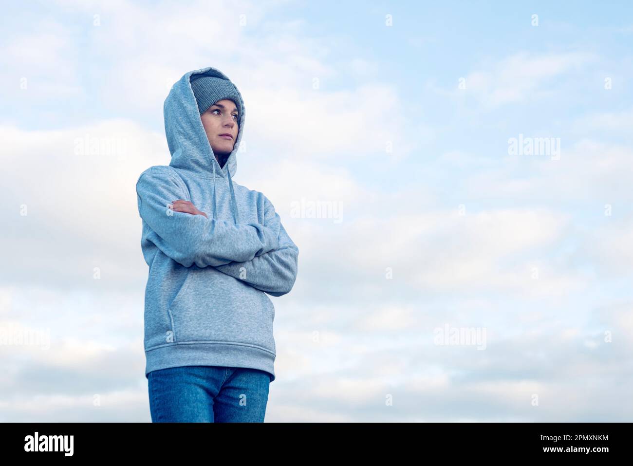 Donna media adulta che indossa una felpa con cappuccio esterna che guarda depressa. Foto Stock