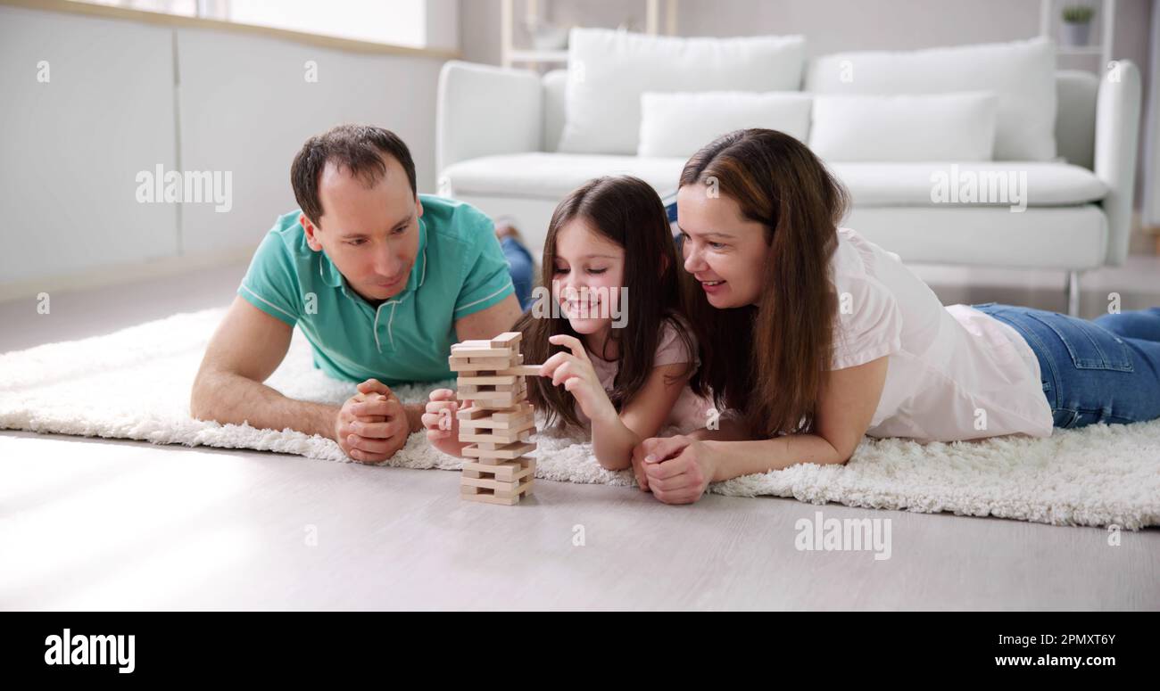 La famiglia felice la posa sul tappeto a giocare con i blocchi di legno a casa Foto Stock