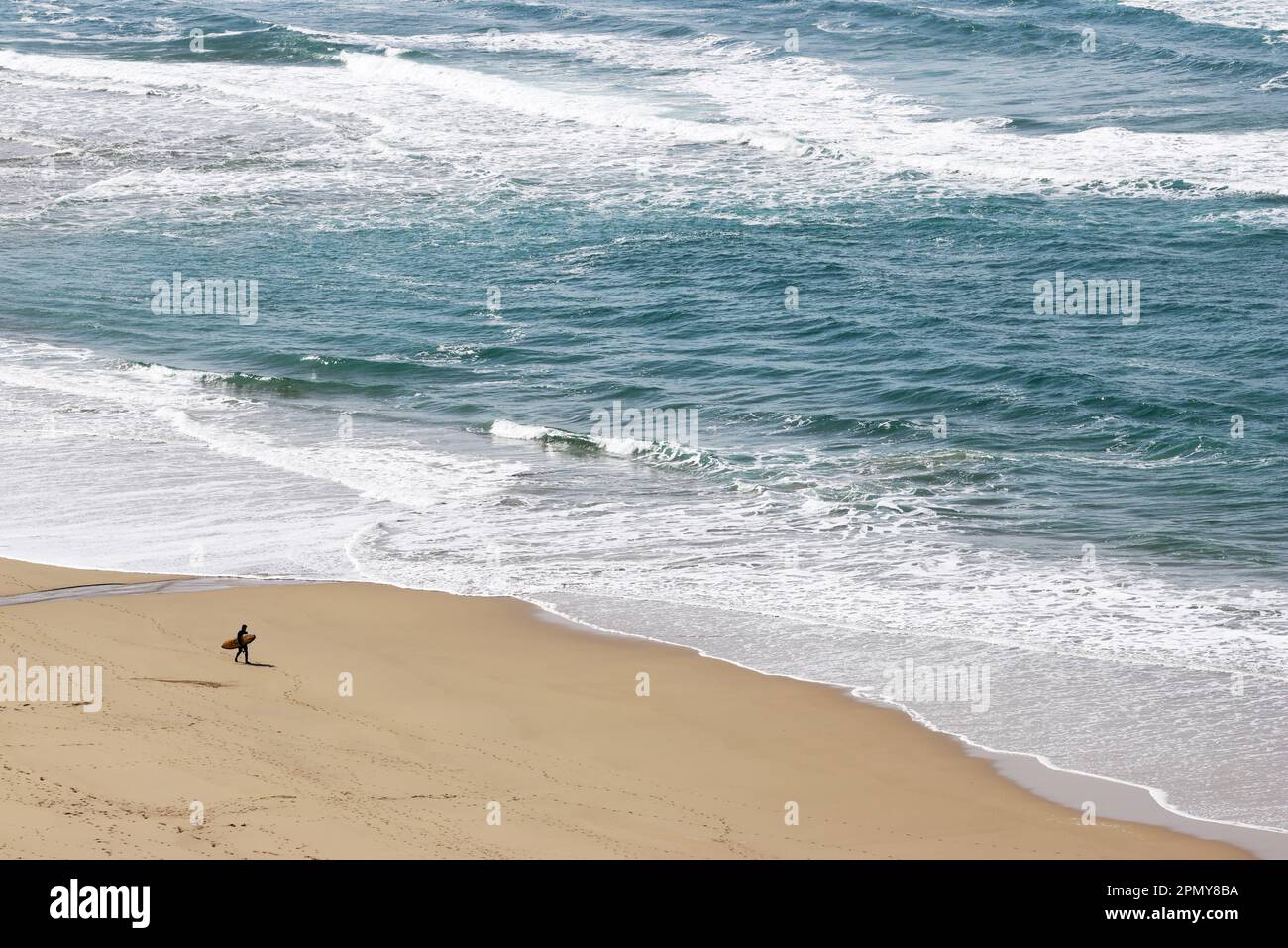 Piccola figura solista sulla spiaggia sabbiosa, contemplando le onde dell'oceano Foto Stock