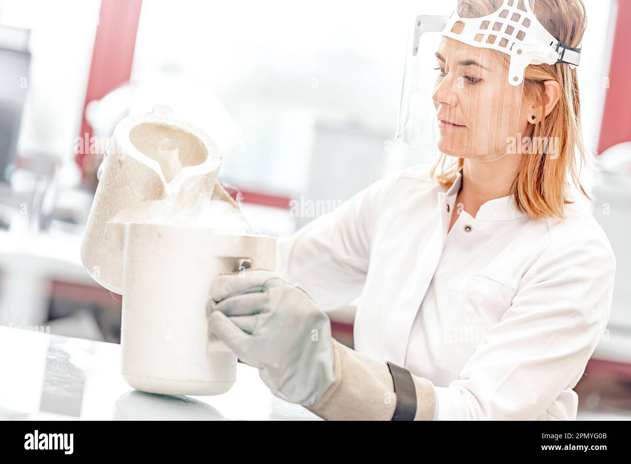 la ricerca con azoto liquido in laboratorio è condotta da una giovane scienziata femminile con maschera protettiva in vetro Foto Stock