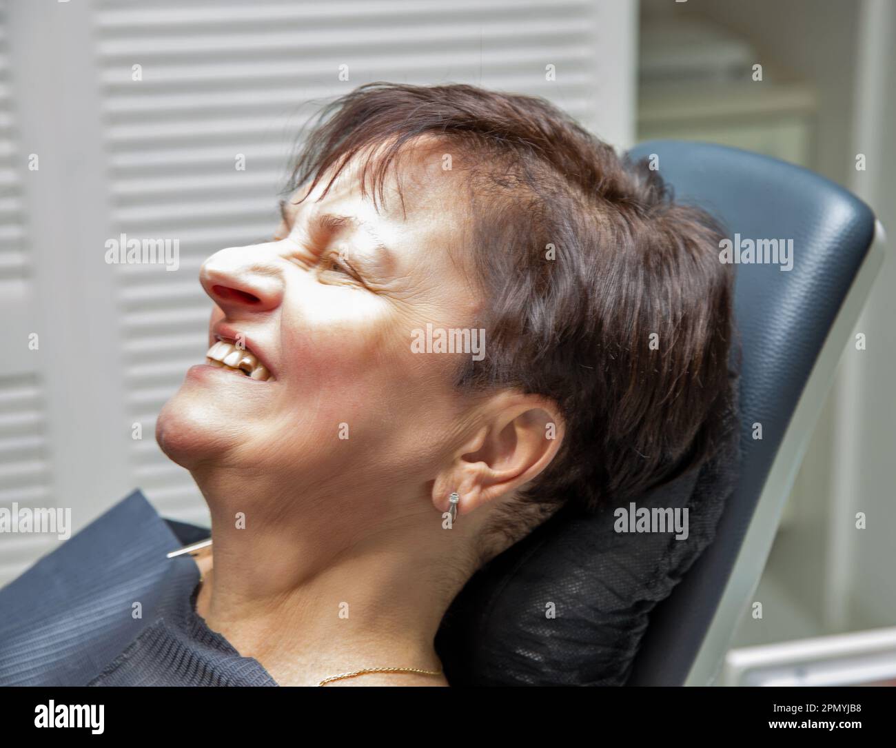 Donna caucasica di mezza età con denti rotti visite dentisti stanza ufficio in una sedia closeup. Foto Stock